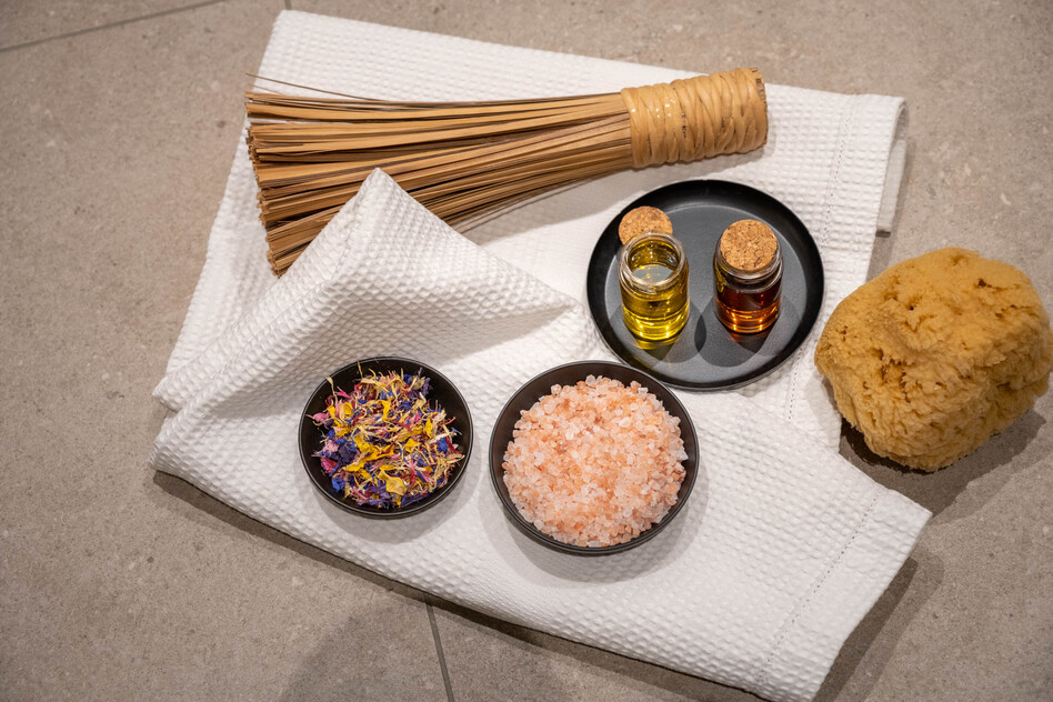 Spa-Arrangement im Seegut Zeppelin mit Körperbürste, Ölfläschchen, getrockneten Blüten, rosa Salz und Naturschwamm auf einem Handtuch