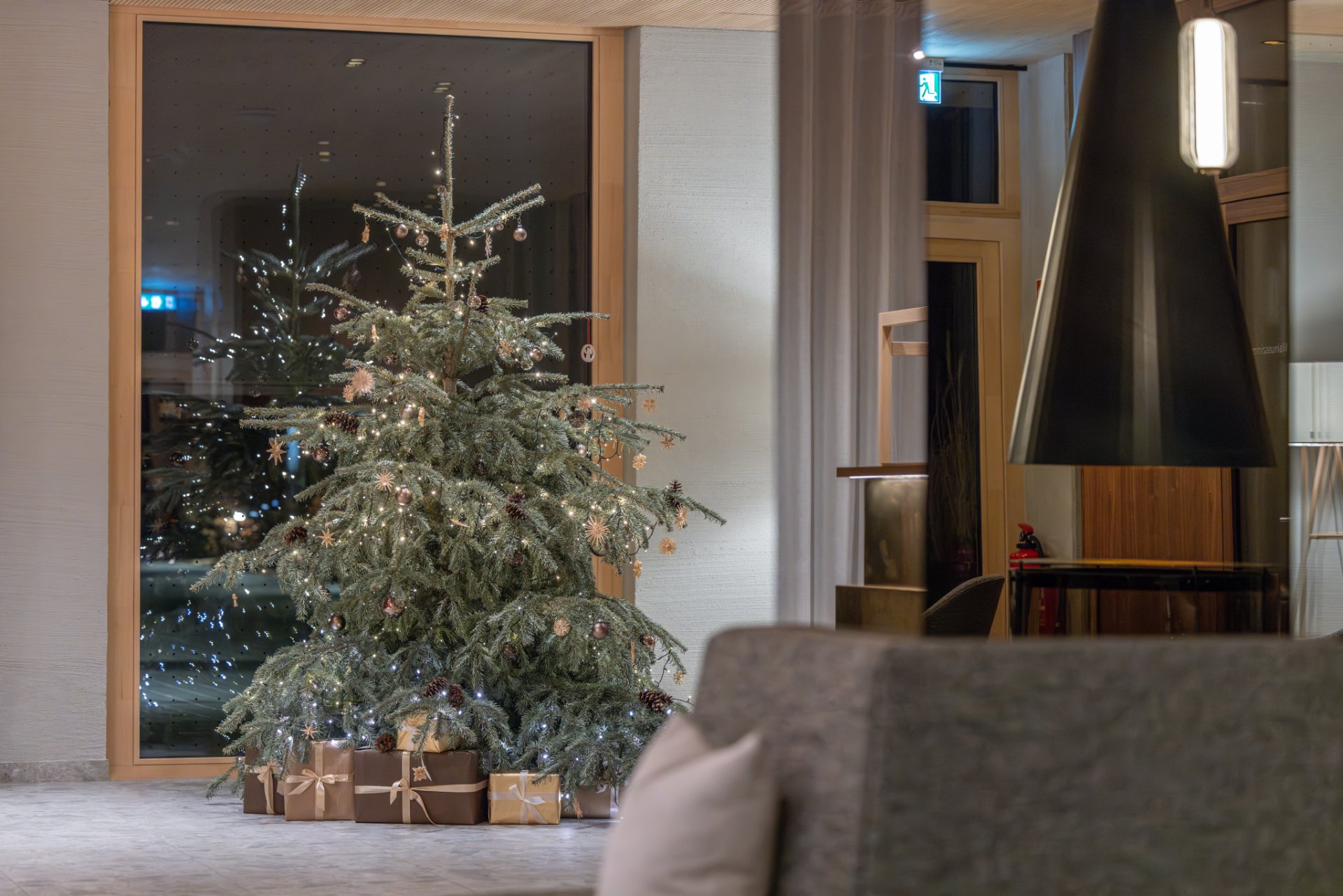 Geschmückter Christbaum neben dem Kamin in der Lobby des Seegut Zeppelin am Bodensee am Abend