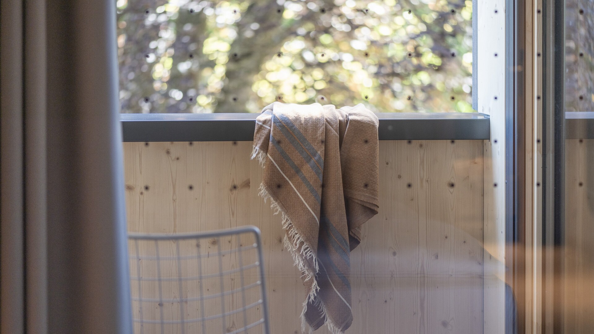 Hotelzimmer im Seegut Zeppelin mit Holzvertäfelung, Sitzgelegenheit und Fensterblick in den Garten