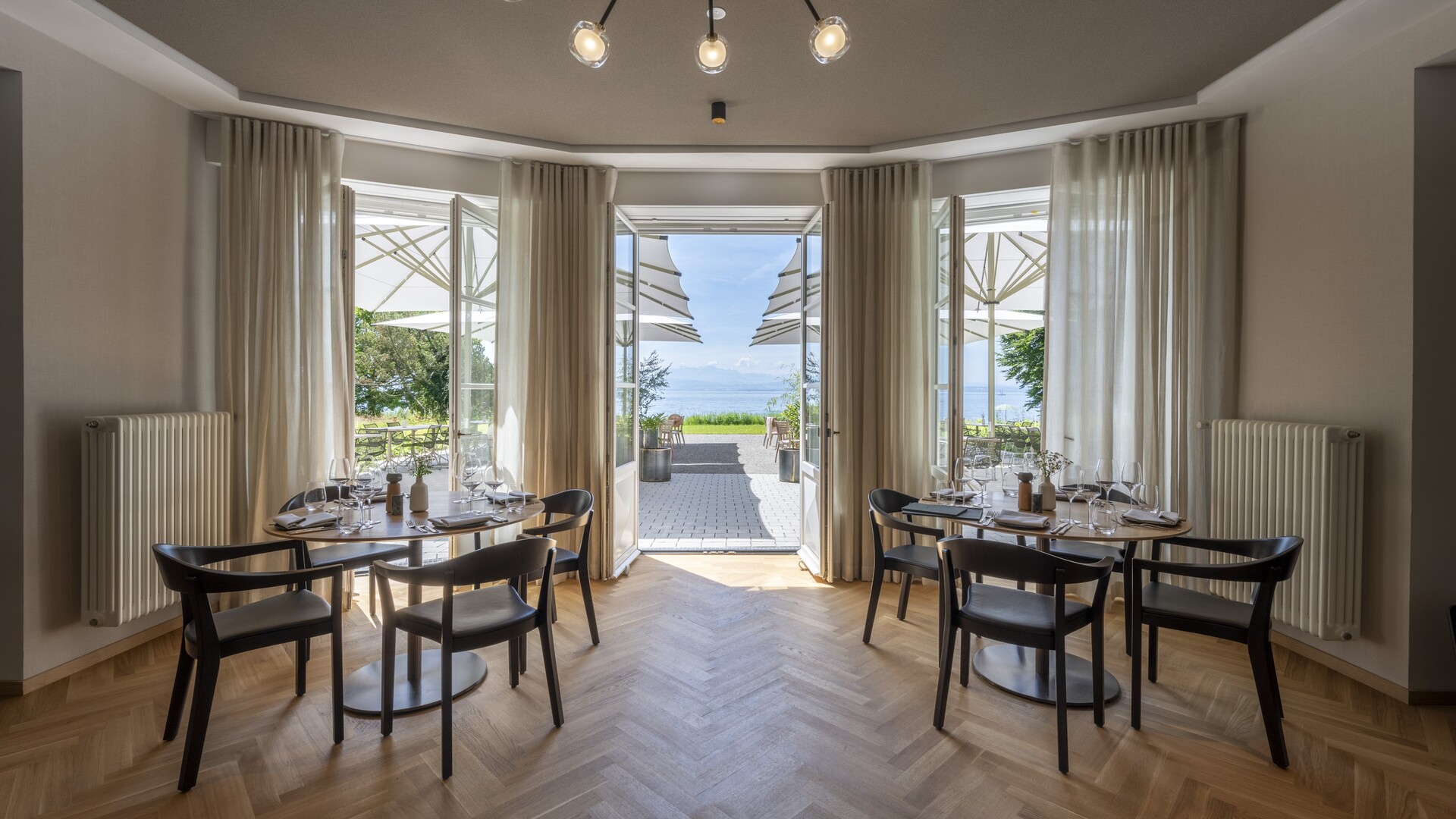 Speiseraum im Restaurant Pinus mit gedeckten Tischen, Kronleuchter und Flügeltüren zur Terrasse mit Seeblick