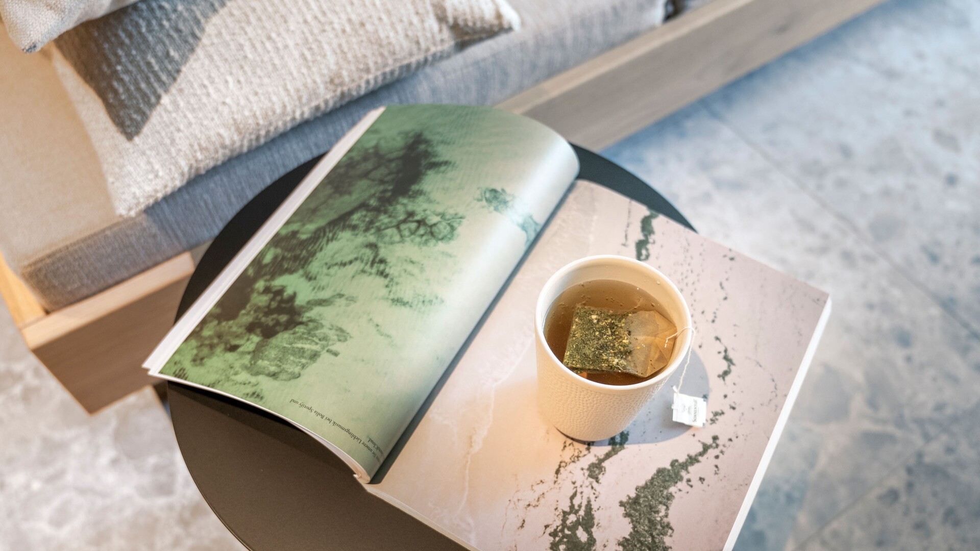 Teeschale und aufgeschlagenes Buch auf einem Beistelltisch im Garten Spa des Seegut Zeppelin am Bodensee