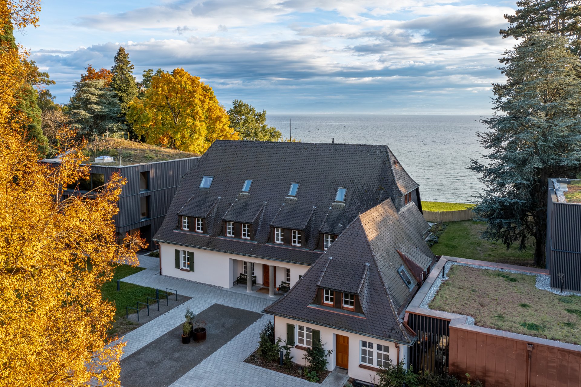 Luftaufnahme des Seegut Zeppelin im Herbst: Villa zwischen bunten Bäumen am Bodensee in Friedrichshafen