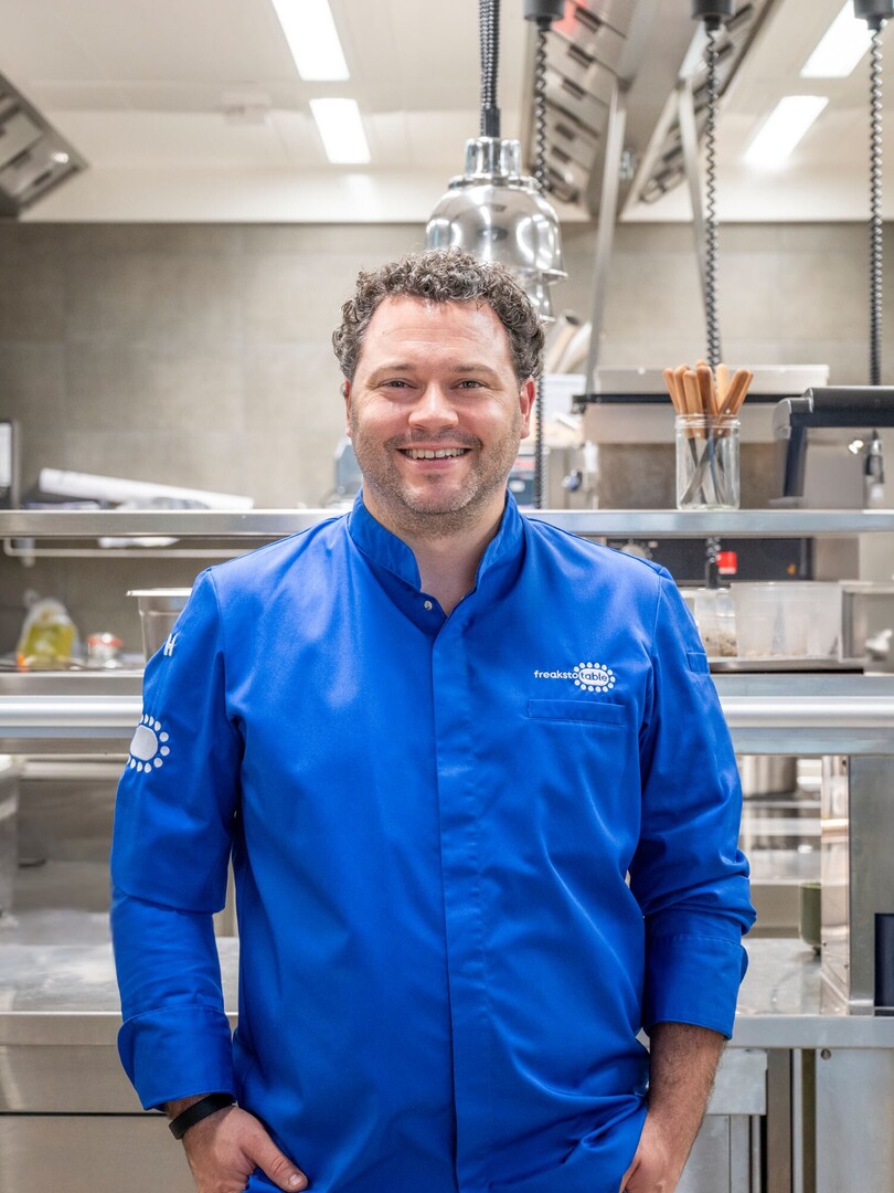 Küchenchef Philipp Heid in blauer Kochjacke in der Küche des Seegut Zeppelin