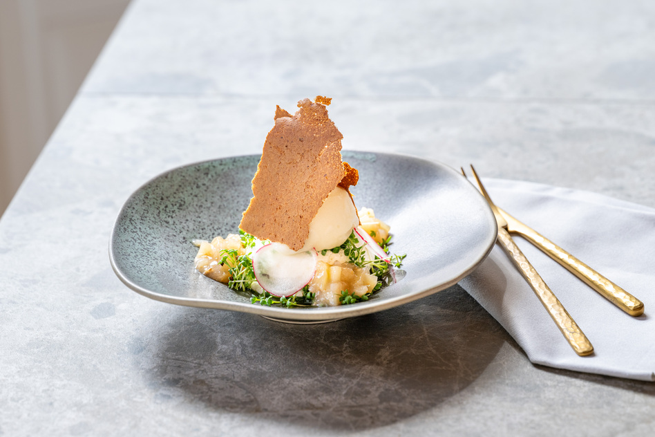 Angerichtetes Gericht auf grauem Teller mit Waffel und goldenem Besteck im Restaurant Pinus des Seegut Zeppelin