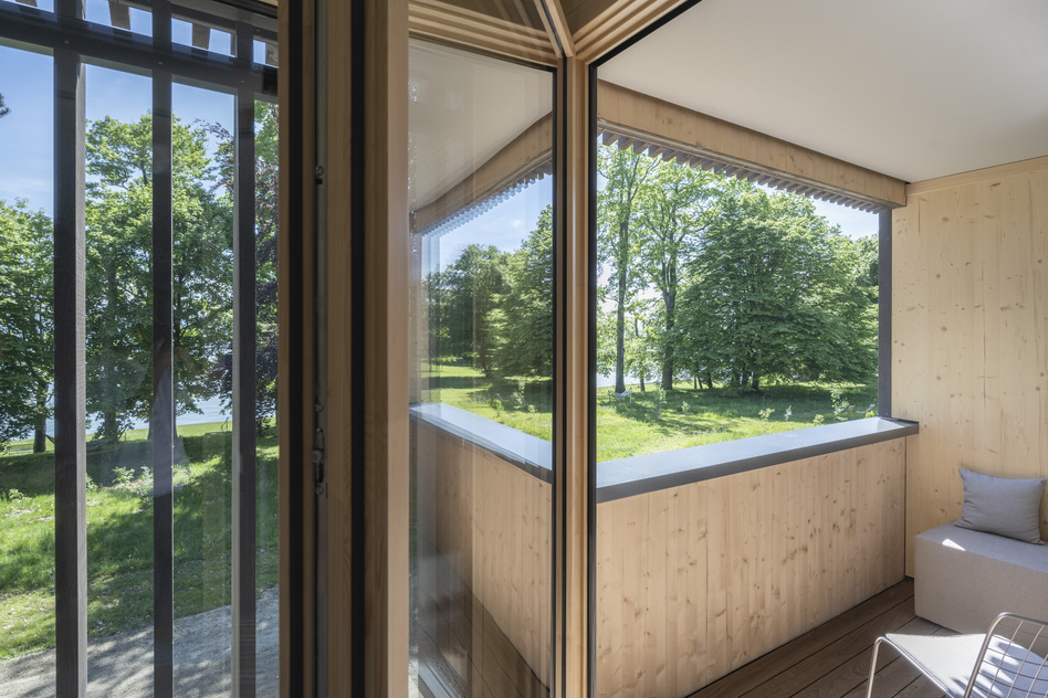 Zimmer im Haus Helene des Seegut Zeppelin mit bodentiefen Fenstern und Blick auf Wiese und Bäume