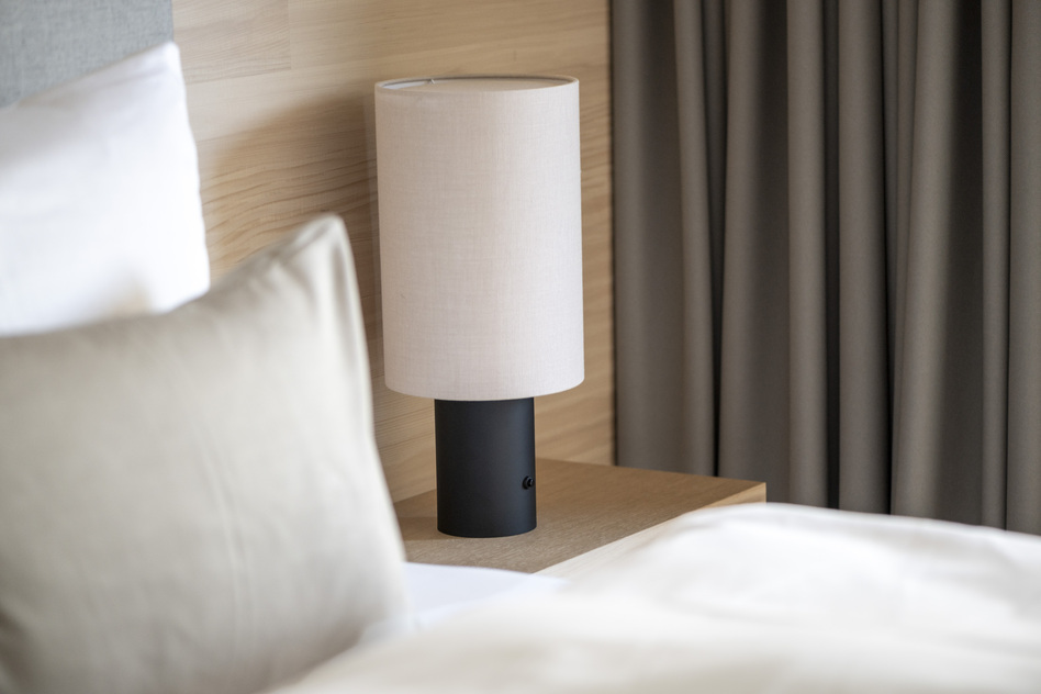 Nachttisch mit Leuchte, Kissen und Bett in einem Hotelzimmer im Seegut Zeppelin