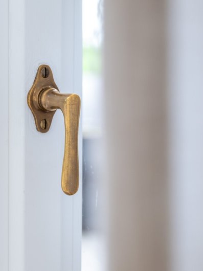 Detailaufnahme eines messingfarbenen Türgriffs an einer weißen Tür in der Villa Gminder