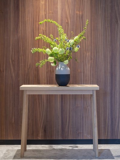Holzkonsole an einer Wand aus Nussbaumholz mit einer Vase mit Blumen im Seegut Zeppelin