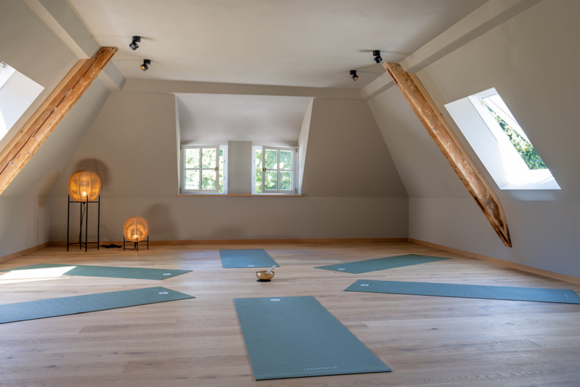 Yogaraum unter dem Dach im Seegut Zeppelin mit Holzbalken, Dachfenstern und ausgelegten Yogamatten