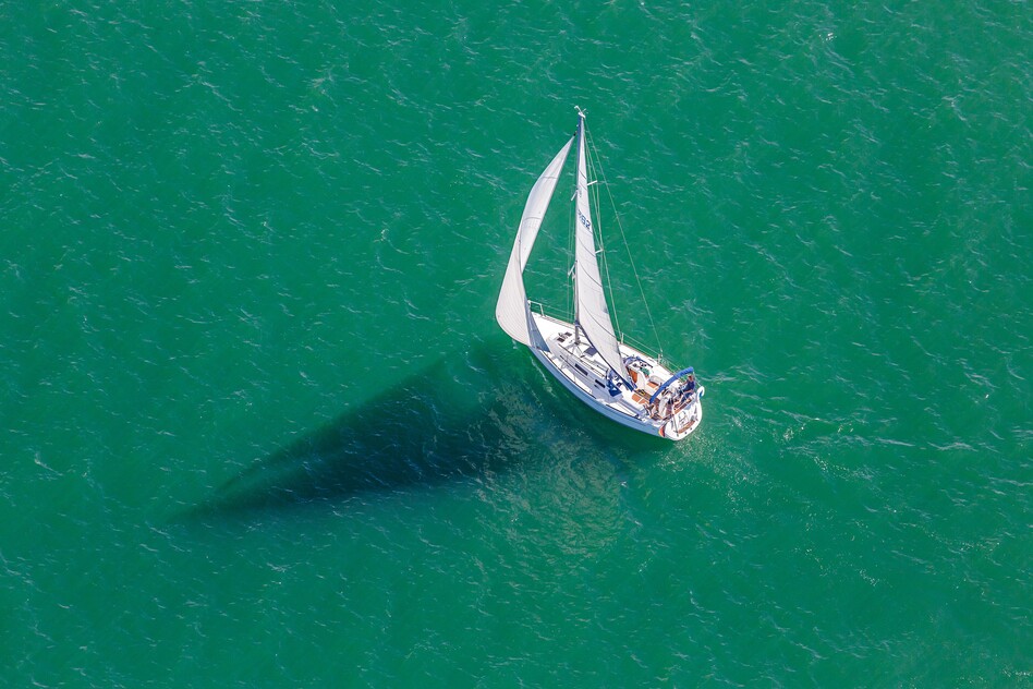 Luftaufnahme einer Segelyacht auf dem türkisfarbenen Wasser des Bodensees